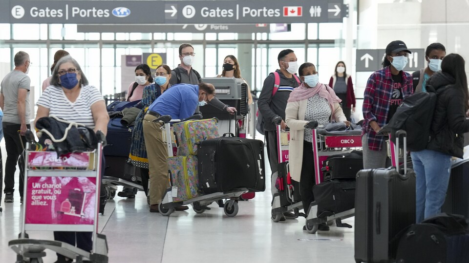 Des personnes font la queue pour s'enregistrer à l'aéroport international Pearson de Toronto.