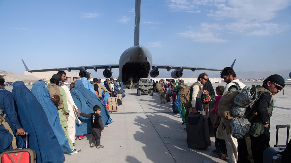 Des arrimeurs et des pilotes de l'armée de l'air américaine supervisent l’embarquement des passagers à bord d'un C-17 Globemaster III.