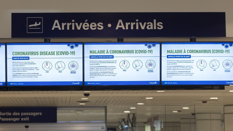 Des messages en lien avec la pandémie de la COVID-19 diffusés sur des écrans à l'aéroport de Montréal.