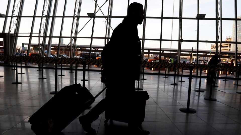 Un voyageur traînant sa valise dans un aéroport.