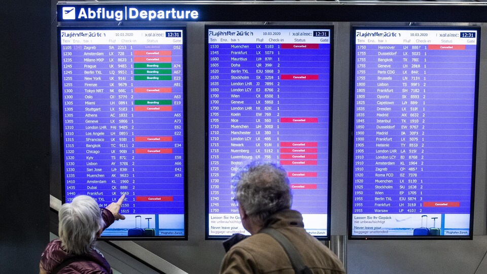 Un couple regarde le tableau des départs à l'aéroport de Zurich.