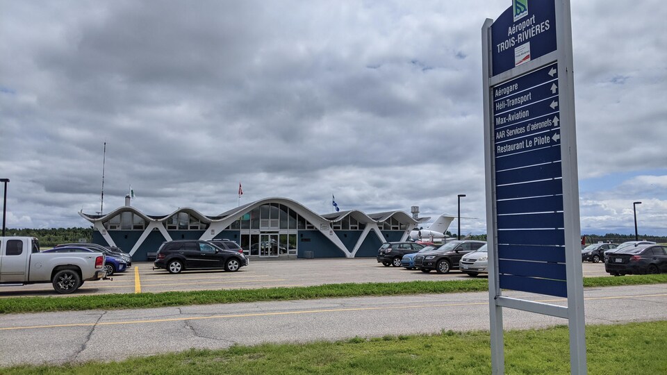L'aéroport de Trois-Rivières. Des voitures sont stationnées devant le bâtiment.