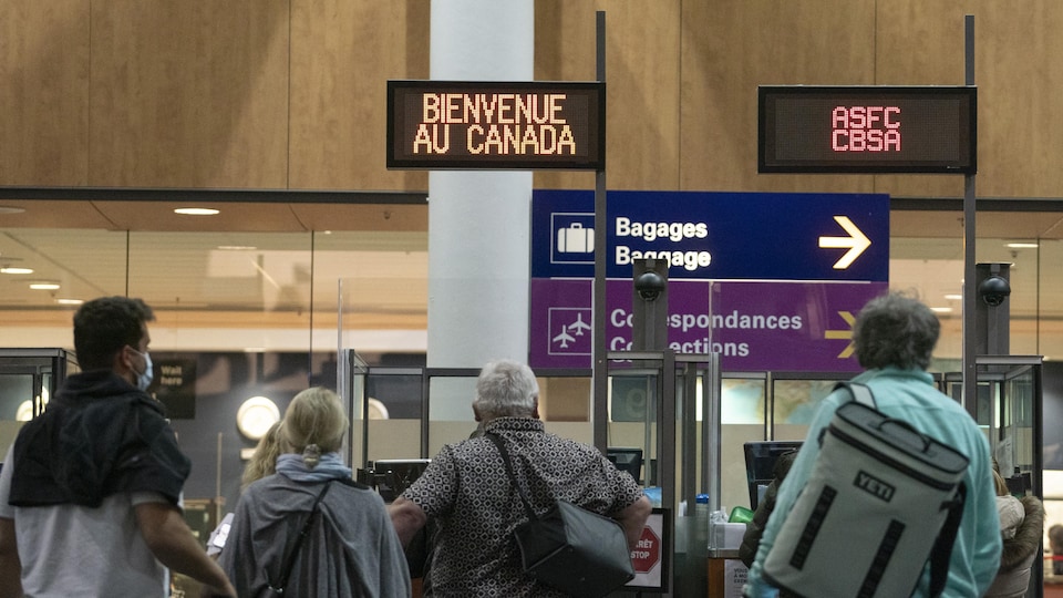 Des passagers avancent vers l’accueil aux douanes canadiennes à l’aéroport international Trudeau à Montréal pour les formalités d'entrée au pays.  