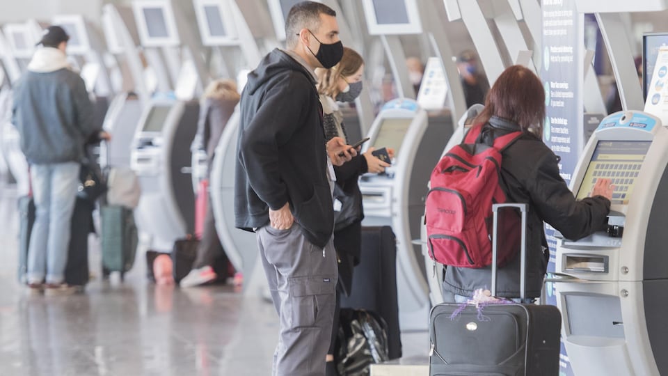 Des voyageurs avec leurs valises à l'aéroport Trudeau.