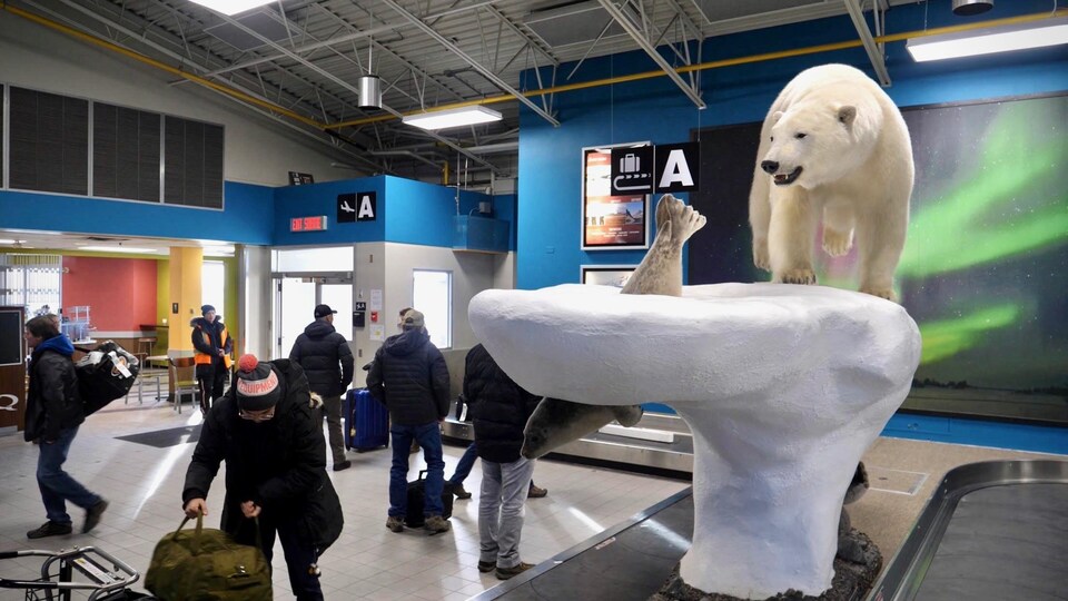 Des voyageurs récupèrent leurs valises dans un caroussel.