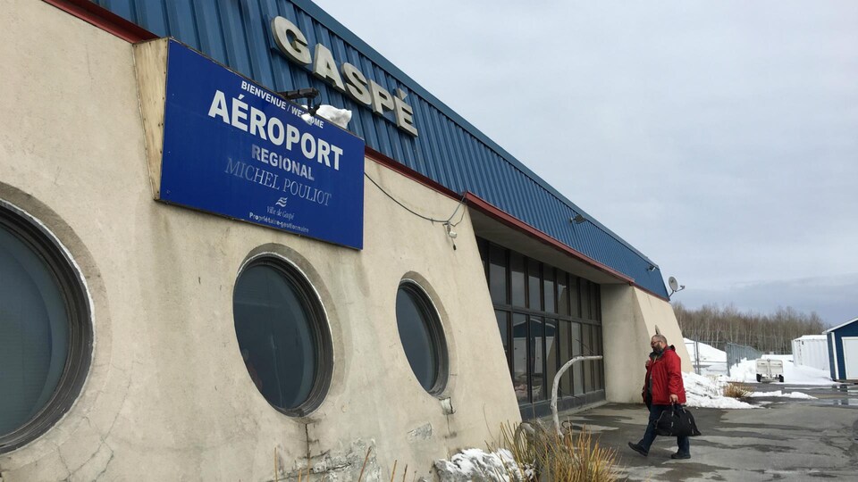 Entrée extérieure de l'aéroport avec affiche.