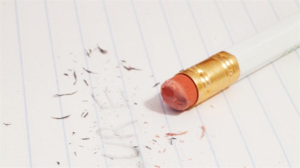 Un mot écrit au crayon effacé sur une page, le crayon est posé sur la page