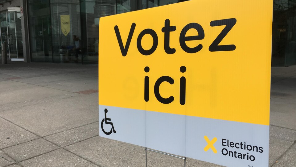 Une affiche jaune qui dit : Votez ici.
