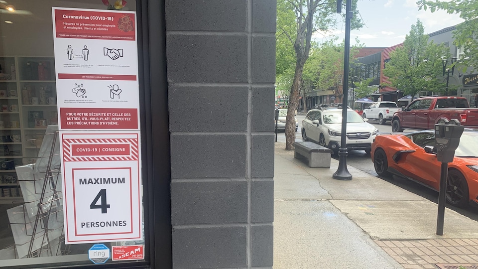 Une affiche dans la fenêtre d'un commerce indique maximum 4 clients.