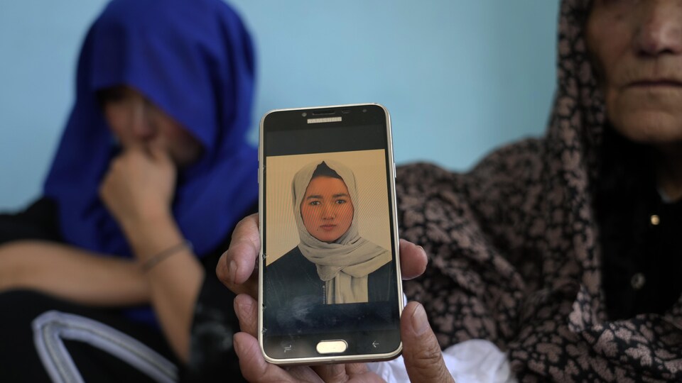 Une femme âgée montre la photo d'une jeune femme sur un cellulaire.