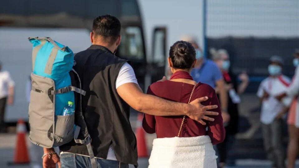 Deux réfugiés afghans transportent leur sac à dos en direction d'un autobus.