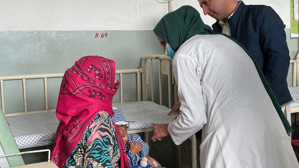 Des travailleurs de la santé et une patiente avec un bambin dans les bras.