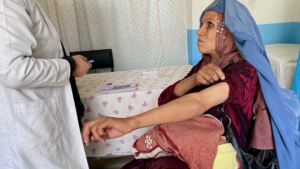 Un médecin et une patiente qui retrousse une manche.