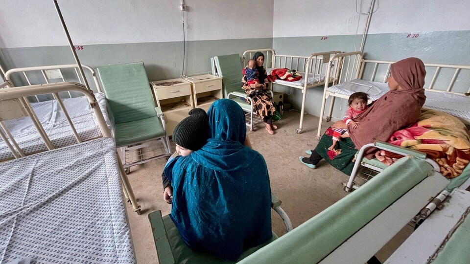 Trois femmes tenant des enfants dans leurs bras dans une chambre d'hôpital.