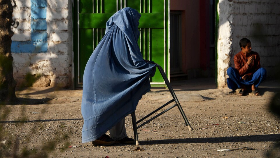 Une femme voilée se déplace à l'aide d'un déambulateur.