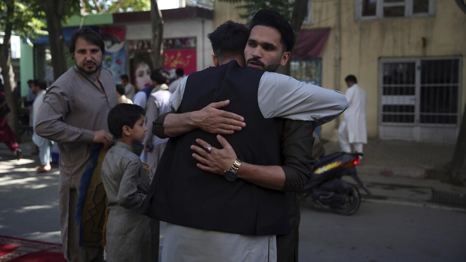 Accolade entre deux hommes au sortir d'une mosquée dans une rue animée de Kaboul en Afghanistan.