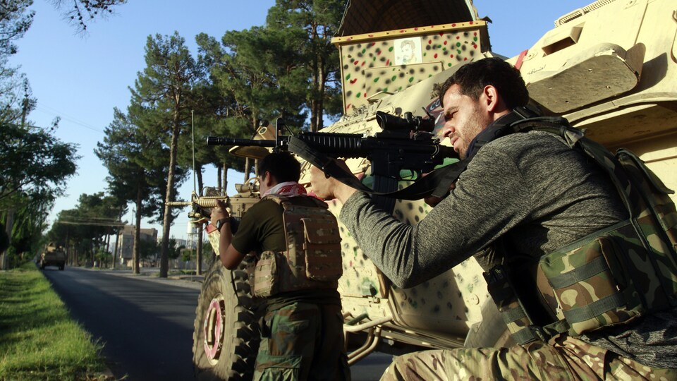 Des soldats prennent position, protégés par leur véhicule blindé.