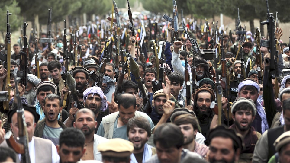 The assembled men raise their guns in the air.