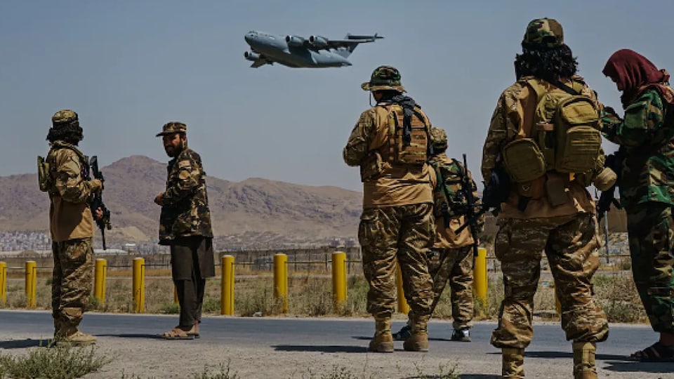 Des soldats talibans observent un avion  américain quitter Kaboul.