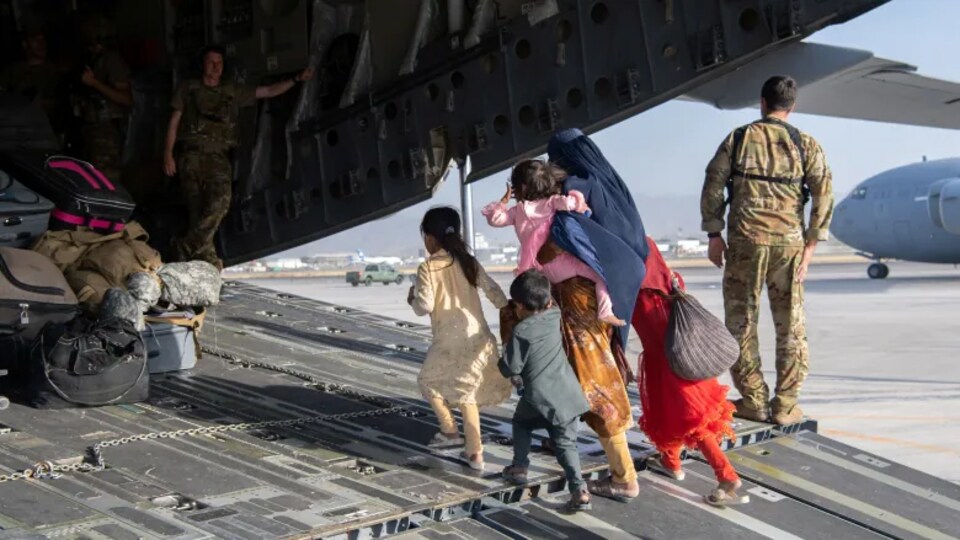 Un famille afghane embarque dans un avion militaire américain.