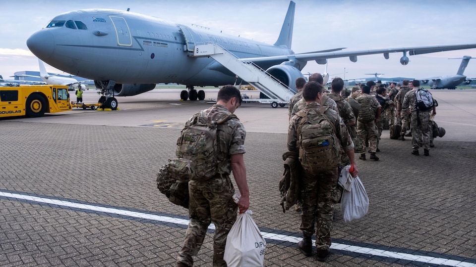 Les militaires américains marchent en rang vers un avion sur le tarmac.