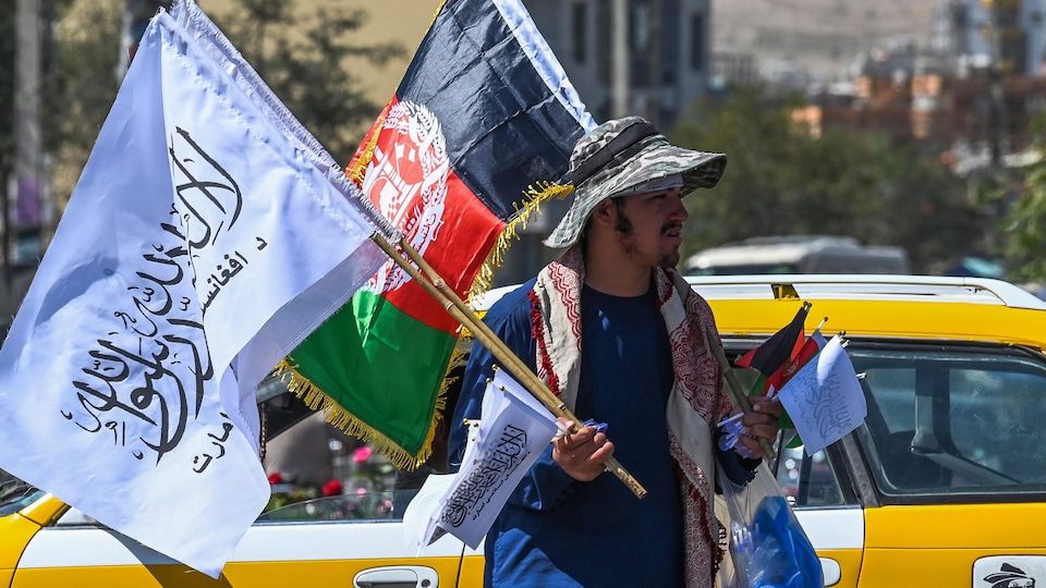 Un homme porte des drapeaux des talibans et de l'Afghanistan de différentes tailles.