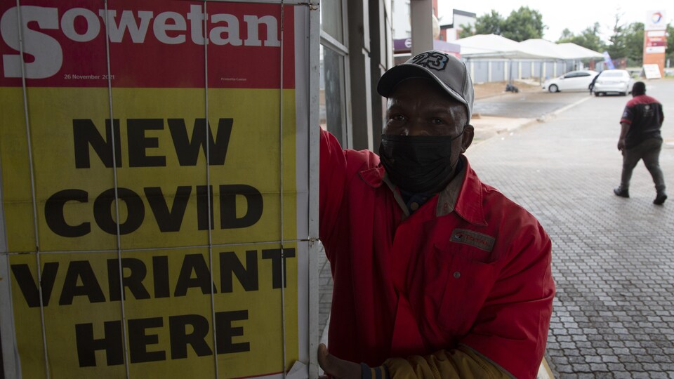 Un employé d'une station-service tient une affiche sur laquelle apparaît la une d'un journal de Pretoria.
