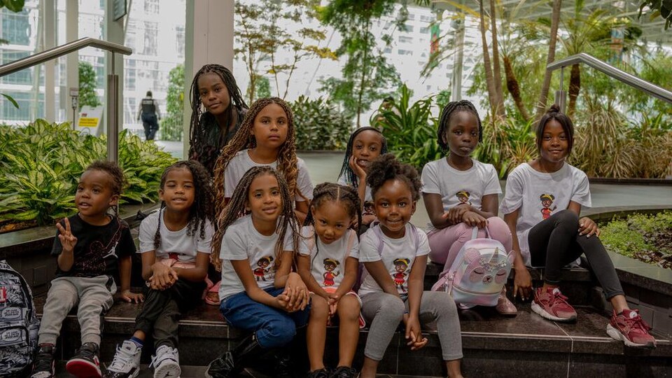 Des enfants noirs entourés de plantes dans un corridor de l'Université de Regina.