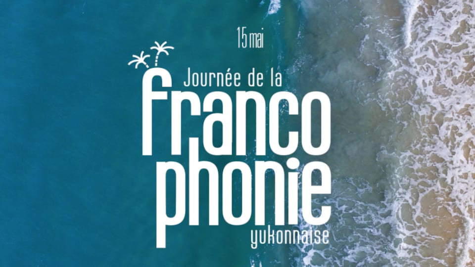 Une inscription annonçant la journée de la francophonie yukonnaise au-dessus d'une plage.
