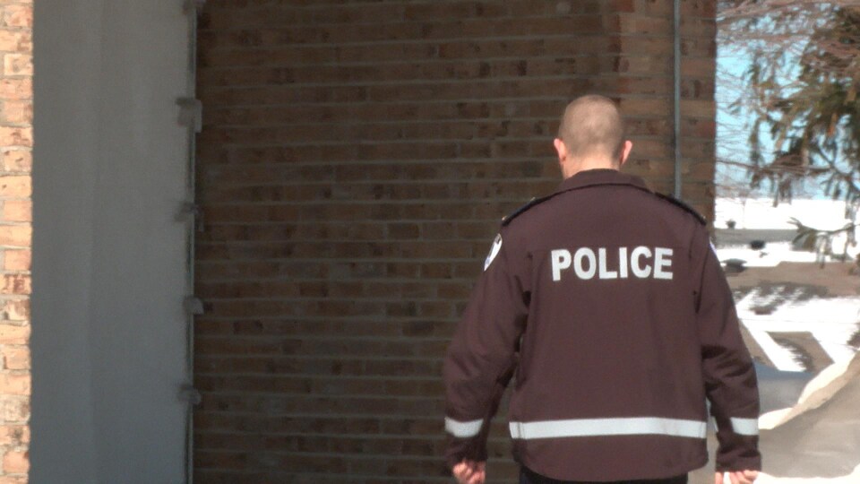 Un agent du Service de police de la Ville de Lévis de dos portant un manteau indiquant « police ».