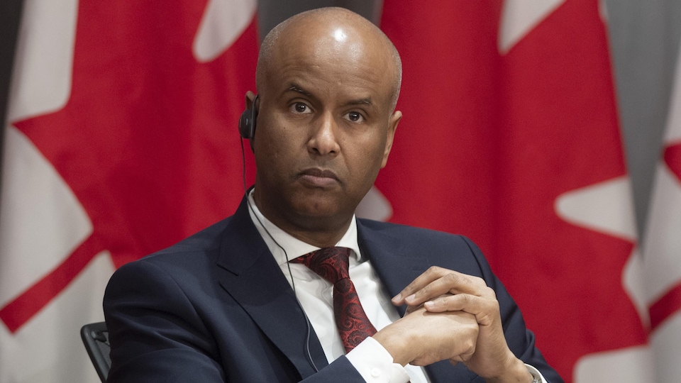 Ahmed Hussen, assis sur une chaise, écoute dans son oreillette.