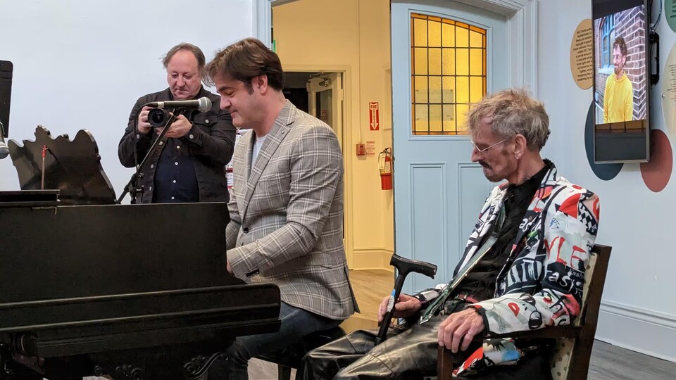 Mark Asselin est assis près de son ami, Igor Vrabac, qui joue au piano.