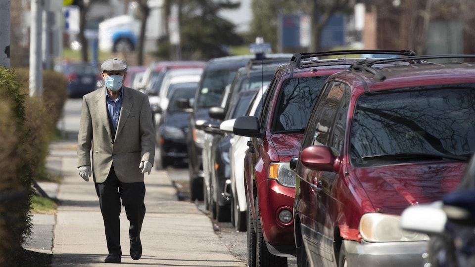 Une personne âgée portant un masque marche dans un quartier de Montréal-Nord.