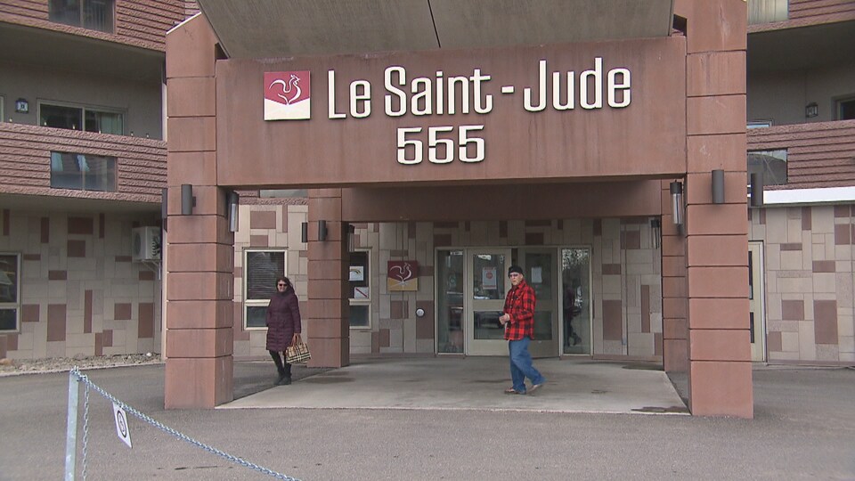 Deux personnes marchent devant une résidence pour personnes âgées.