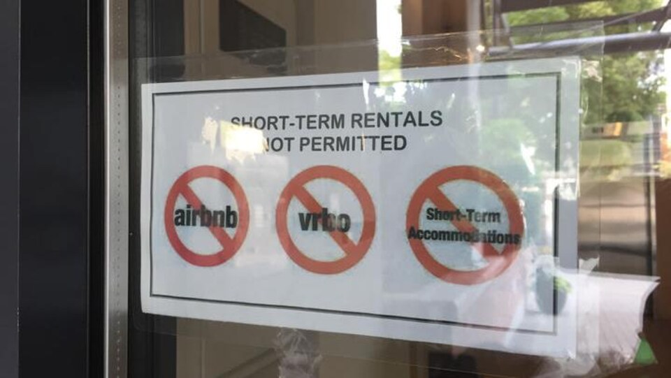 Une affiche collée dans la vitre d'un immeuble indique que les locations à court terme y sont interdites.