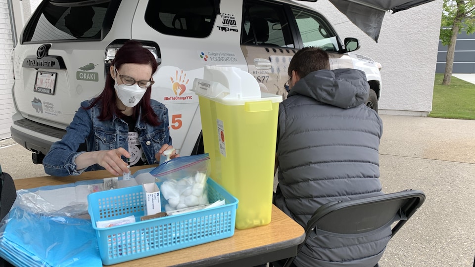 Une femme se prépare à vacciner un homme installé à une station ambulante de vaccination mise sur pied par l'opération Aisokinakio’p.