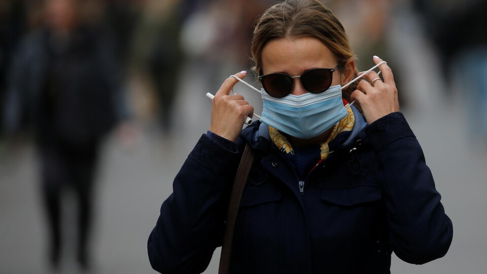 Une passante qui porte des lunettes fumées ajuste son masque dans une rue de Kiev le 22 octobre 2020.