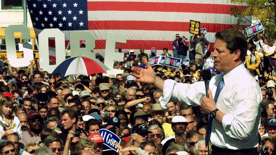 Al Gore s'adresse à une foule avec, en arrière-plan, un drapeau américain format géant.