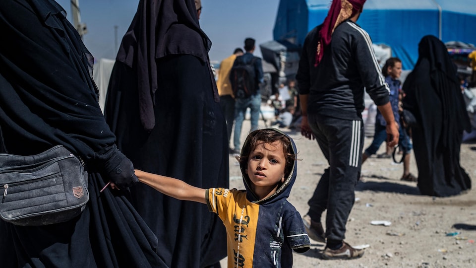 Un enfant tient la main d'une femme couverte d'un tchador.
