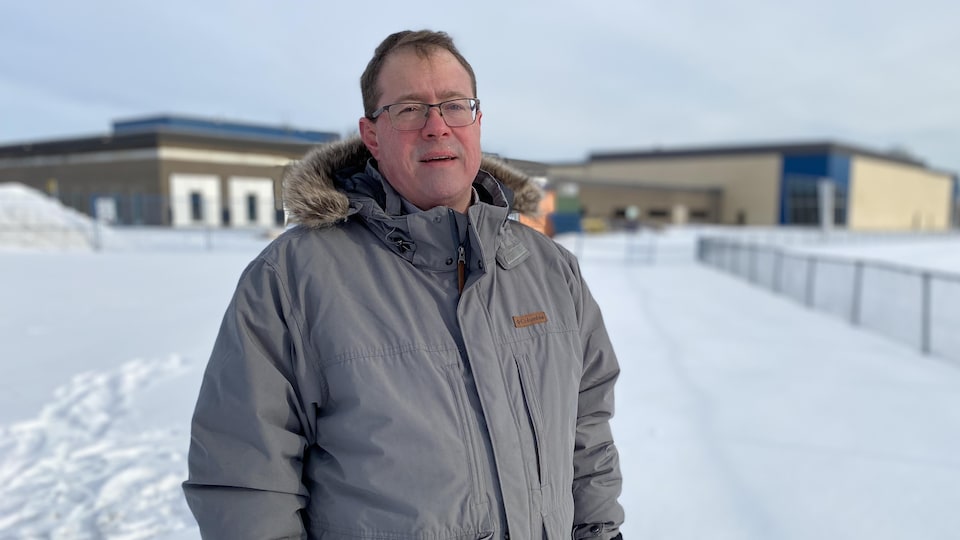 Alain Gauthier pose devant le chantier de l'École secondaire Mont-Bleu en hiver.