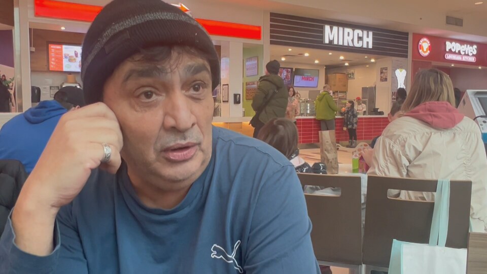 Alain Marc Lévy est accoudé à la table d'un restaurant dans un centre commercial.