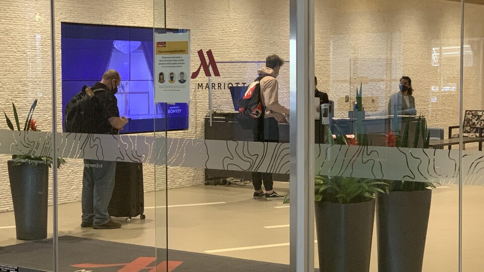 Des voyageurs attendent en ligne pour pouvoir s'enregistrer à l'hôtel Marriott de l'aéroport de Calgary.