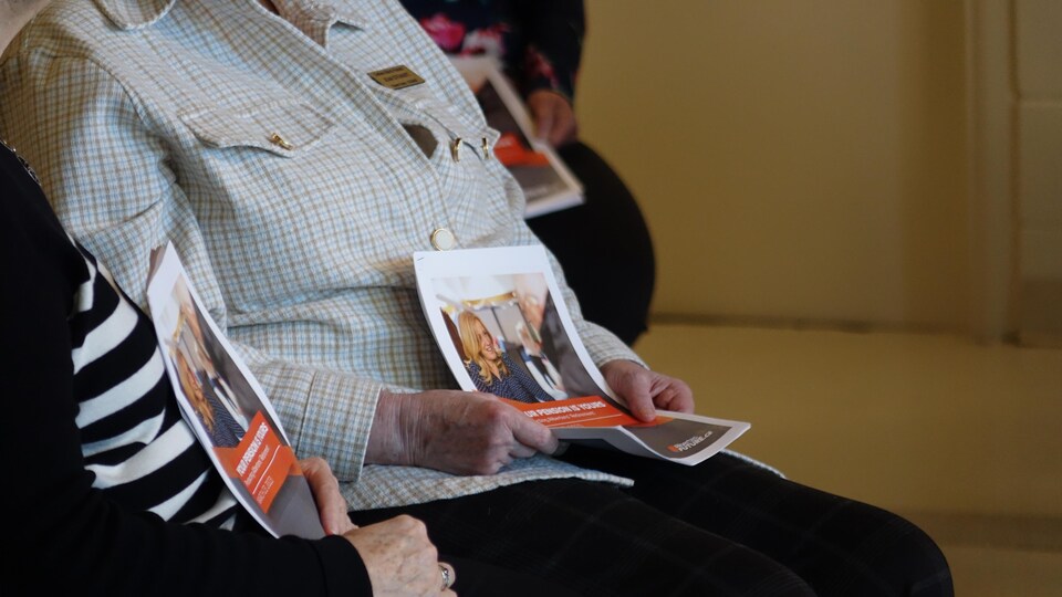 Deux personnes tiennent un pamphlet du Nouveau Parti démocratique de l'Alberta.