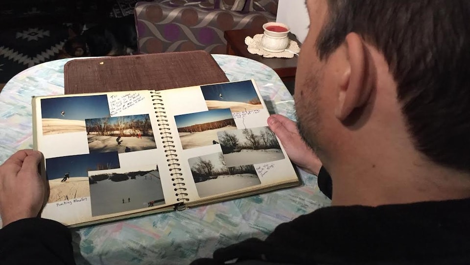 Un homme, vu de dos, qui regarde un album de photos