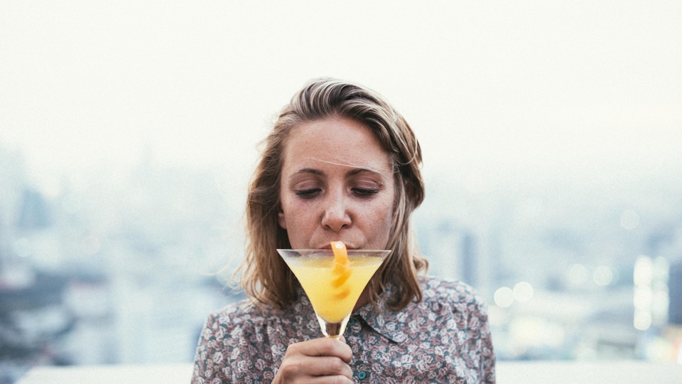 Une femme boit une boisson alcoolisée. 