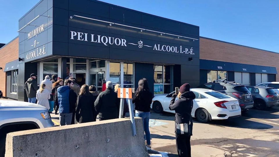 Des clients à l'extérieur d'un magasin qui vend de l'alcool.