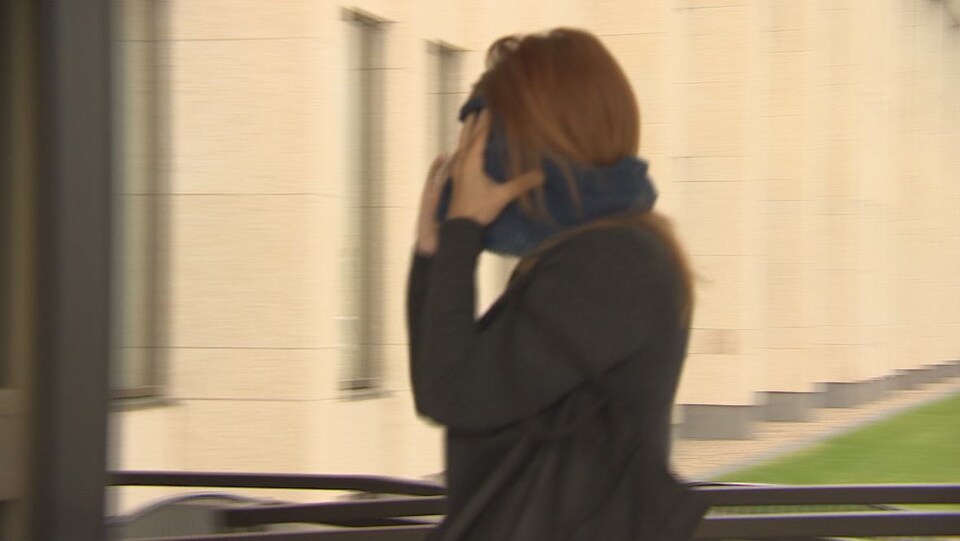 Une photo floue d'une femme marchant en se couvrant le visage.