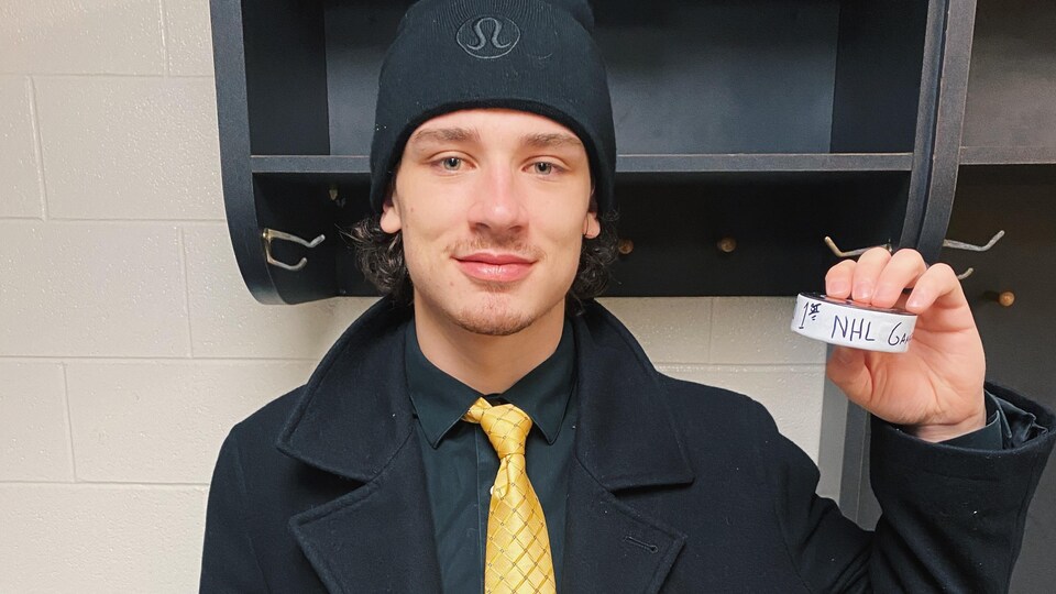 Alex barré-Boulet pose avec en mains la rondelle de son premier match dans la LNH.