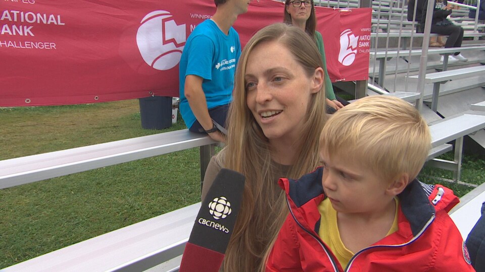 Une mère de famille avec son enfant répond aux questions de Radio-Canada.