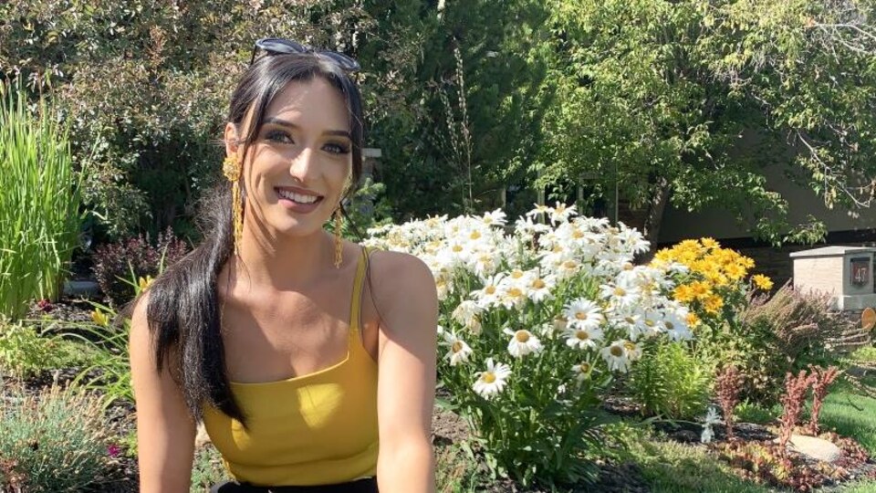 Alexandra Tremblay, assise dans l'herbe devant des fleurs.